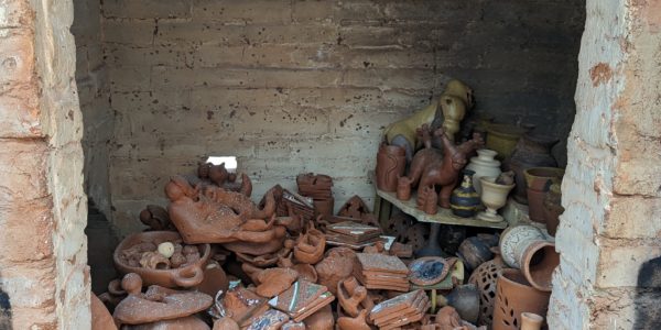 Looking through the open door of a brick kiln, we see ceramic vases, bowls, and dishes piled on top of each other with a thin layer of ash coating everything.